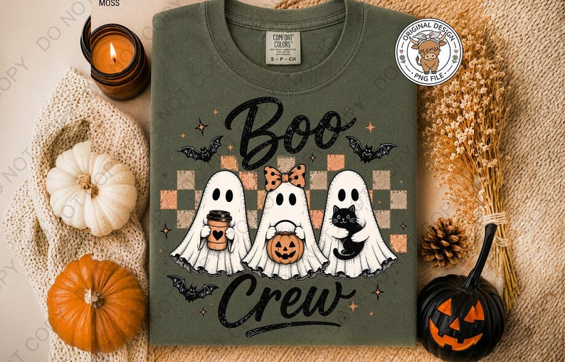 May include: An olive green crewneck t-shirt featuring a graphic of three ghosts with the text "Boo Crew". The ghosts are holding a coffee cup, a pumpkin bucket, and a black cat. The design includes a checkered background, bats, and stars.