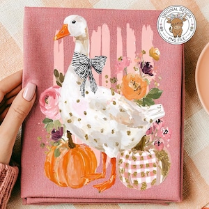 May include: A pink tea towel featuring a white goose with a black and white bow tie, surrounded by flowers and pumpkins. The towel has a decorative design with the words "Original Design PNG File" in a circle.