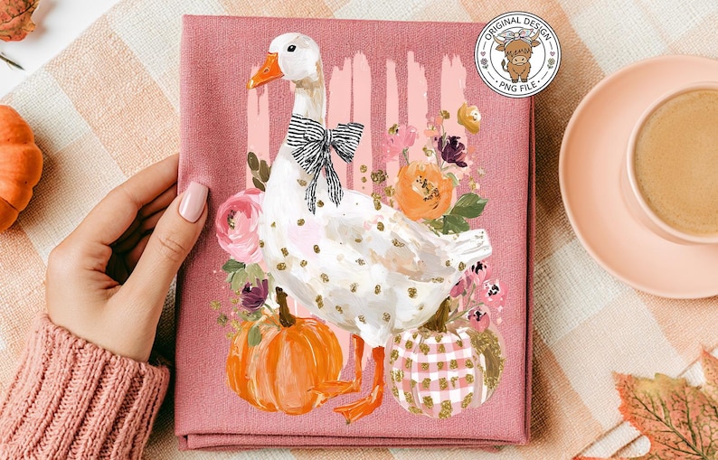 May include: A pink tea towel featuring a white goose with a black and white bow tie, surrounded by flowers and pumpkins. The towel has a decorative design with the words "Original Design PNG File" in a circle.