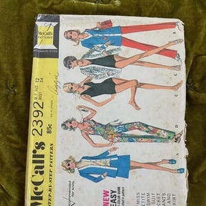 Może przedstawiać: Vintage wzór krawiecki McCall's 2392. Okładka przedstawia ilustracje kobiet w różnych strojach, w tym kostium kąpielowy, kurtka, spodnie i spódnica. Wzór jest dla rozmiarów Miss Petite, obwód biustu 86 cm. Cena: 85 centów.