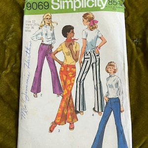 May include: Vintage Simplicity sewing pattern 9069. The pattern features illustrations of flared pants and blouses. The package is white with green and yellow accents, and includes the text "Simplicity" and "Size 12".