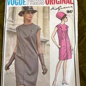 May include: Vintage Vogue Paris Original sewing pattern from 1947. The pattern shows illustrations of two dresses. One is a grey sleeveless dress with a V-neck design. The other is a pink sleeveless dress. The text "Vogue Paris Original" is at the top.