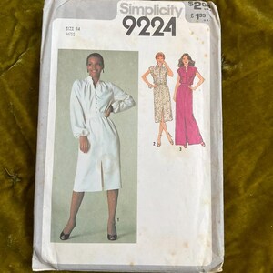 Può includere: Un pacchetto di cartamodelli Simplicity vintage, taglia 14 Miss, con illustrazioni di tre diversi modelli di abiti. Il pacchetto ha uno sfondo bianco con il logo Simplicity e il numero del modello 9224. L'immagine mostra una donna con un vestito bianco.