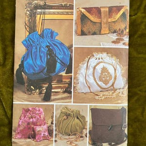 Può includere: Un foglio di modelli Butterick con vari design di borse. Il foglio mostra una borsa blu con coulisse e nappe, una pochette oro e marrone, una borsa bianca con coulisse e pizzo, una borsa floreale rosa, una borsa verde con coulisse e una borsa messenger marrone.