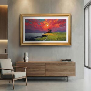 May include: A framed landscape painting shows a sunset over water. The sky is a mix of red and orange, with a small house on the horizon. The painting is in a gold frame, and is a piece of wall art.