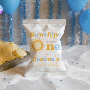 May include: A white chip bag with the text "Our Little Sunshine is turning one. It's Joshua's first birthday" in yellow and blue. The bag has a sun graphic and cloud accents. A silver tray of chips is in the background.