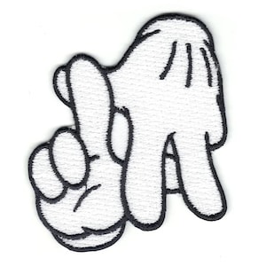 May include: White embroidered patch in the shape of a hand making the "LA" sign, with the index finger and thumb crossed. The patch has a black outline and is on a white background. The patch is likely for clothing or accessories.