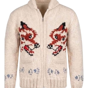 May include: A cream-coloured, long-sleeve, zip-up knit cardigan featuring a shawl collar and two front pockets. The garment displays two symmetrical fox head motifs in shades of red, black, and white, with small paw print patterns along the hem.