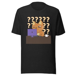 Può includere: T-shirt nero con un disegno di un gatto dei cartoni animati. Il gatto arancione è davanti a un computer viola, sembra stressato. Punti interrogativi gialli sullo sfondo. Una tazza bianca è sulla scrivania.