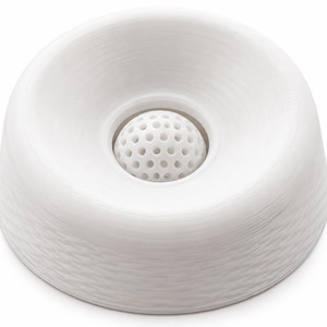 May include: A white, circular, bowl-shaped object with a smooth, sloped exterior and a textured, layered finish. In the centre, there is a small, spherical, white insert featuring a uniform pattern of circular perforations across its surface.