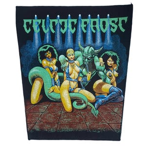 May include: A black fabric patch featuring the text CELTIC FROST in green letters above a graphic illustration of a horned demon figure with two figures, one with a long green snake tail, set against a dark background with blue spotlights.