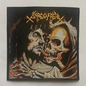 Puede incluir: Un parche cuadrado negro con una ilustración detallada de un rostro humano fusionándose con una calavera. El texto "XARCOFAGOS" está arqueado sobre la imagen en dorado, con "ROTTING" debajo. La obra de arte tiene una apariencia metálica y texturizada.