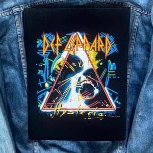 May include: A white ceramic mug with a black handle and the text "But First, Coffee" in a bold, black font. The mug is set against a blurred background, suggesting a cosy setting.