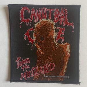 Puede incluir: Un parche cuadrado negro con las palabras "CANNIBAL CORPSE" en rojo goteando sobre una figura marrón en descomposición. Debajo, las palabras "TOMB THE MUTILATED" están en rojo. El parche es de 1993.