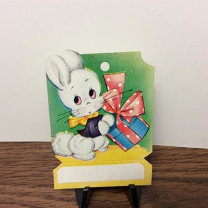 Sweet unused colorful die cut 1940s easter gift card hang tag cute white bunny with big cotton tail and dressed up holds a colorful gift image 1