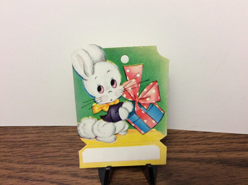 Sweet unused colorful die cut 1940s easter gift card hang tag cute white bunny with big cotton tail and dressed up holds a colorful gift image 1