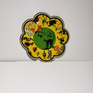 May include: A yellow and green paper plate with a black cat and other Halloween characters. The plate is shaped like a flower.