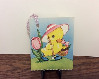 Colorful 1950’s unused die cut easter themed bridge tally card cute duckling dresssed in pink hat with garden tool and basket of tulips