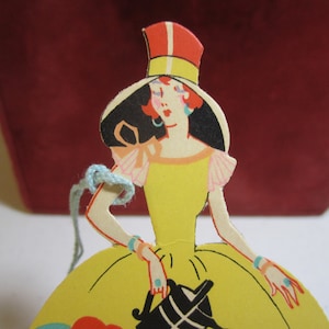1920&#39;s-30&#39;s Deco die cut Gibson bridge tally card lady in big yellow dress and big bonnet watering stylized deco flower garden