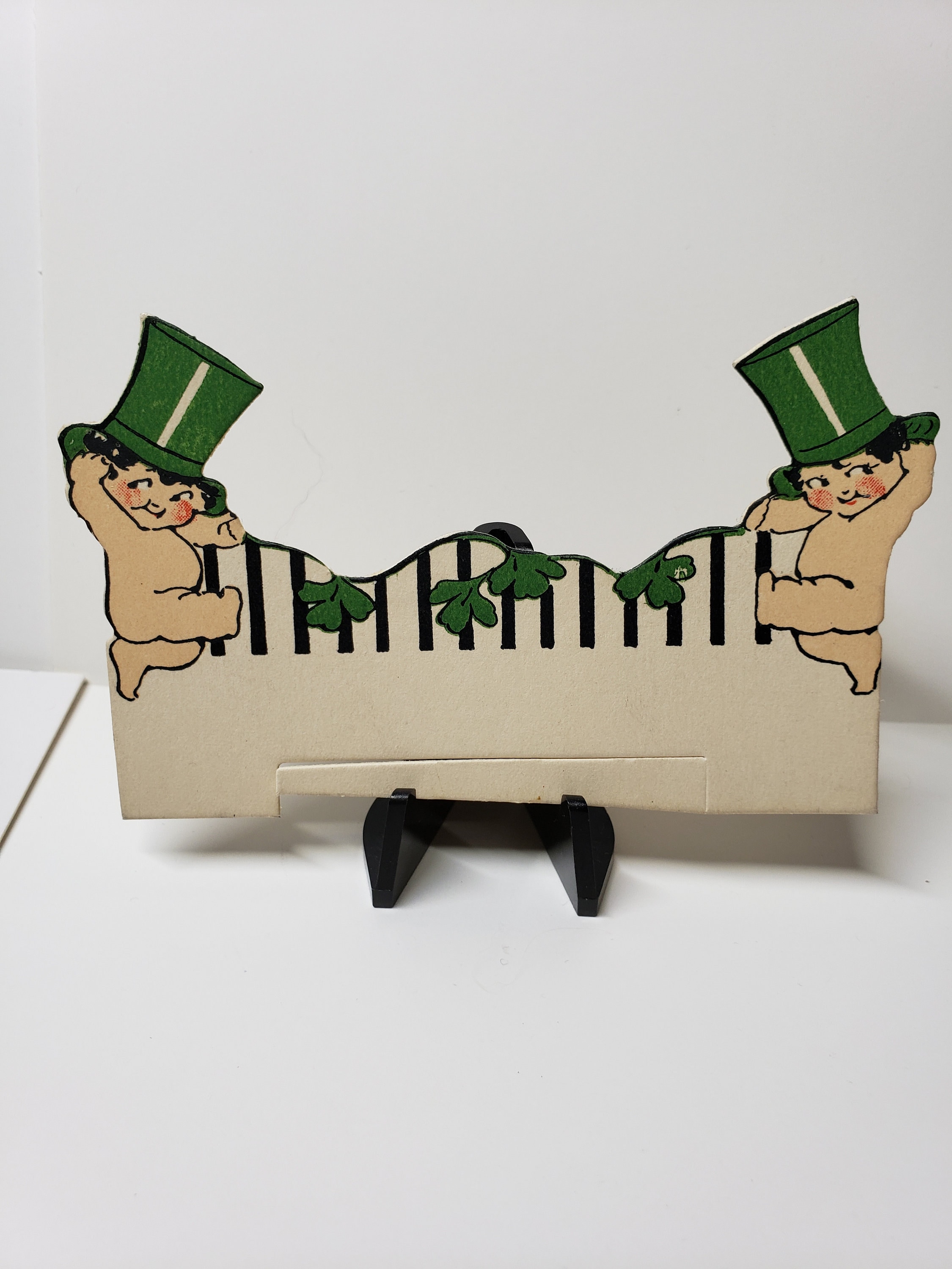 1920s30s unused die cut StPatricks place card 2 adorable dancing cherubic babies kewpies wearing green top hats hold garland