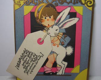 1920's unused P.F. Volland die cut gold gilded easter greetings cardclittle girl gets a hug from cute rabbit, mini card attached with string