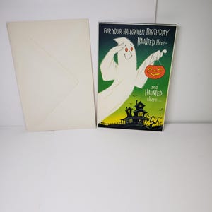 May include: A Halloween-themed greeting card with a white ghost holding an orange jack-o'-lantern. The card reads "FOR YOUR HALLOWEEN BIRTHDAY HAUNTED Here - and HAUNTED there..." An off-white envelope is next to the card.
