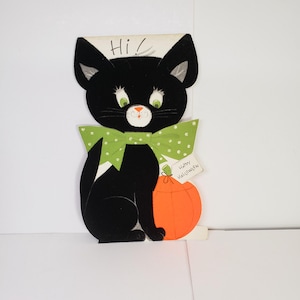 May include: A vintage Halloween greeting card featuring a black cat with green eyes and a green polka-dot bow tie. The cat is holding an orange pumpkin. The card has the words "Hi!" and "Happy Halloween".