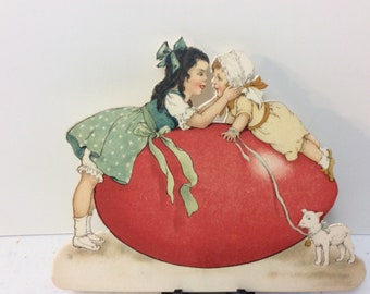 1920’s unused die cut Germany easter place card gigantic red colored easter egg and 2 darling children on top toddler has lamb on lease