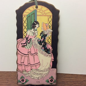 May include: Two women in vintage dresses stand in a doorway. The woman on the left wears a pink dress with black trim and a white lace collar. The woman on the right wears a black and white dress with a white lace collar and a yellow hat. The background is a yellow and green doorway with a black frame.
