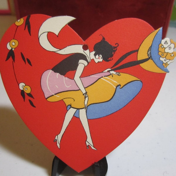 Colorful 1920's-30's unused die cut heart shaped bridge tally card  girl caught in a wind storm wearing deco dress and holding large hat