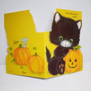 May include: A yellow Halloween greeting card featuring a black kitten with green eyes sitting next to a jack-o'-lantern. A small gray mouse sits atop a plain orange pumpkin. The text on the card reads, On Halloween Night... and Gibson.