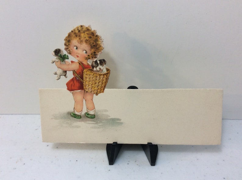 Adorable unused 1920/'s die cut Germany place card sweet little girl holds puppy looks over her shoulder at other puppy in basket on her back