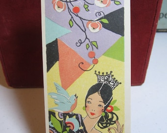 May include: A vintage bookmark featuring a woman with a crown and a blue bird. The woman is wearing a black and white dress with a floral pattern. The background is a colorful geometric design with pink flowers.