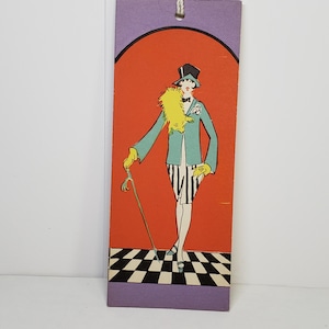 May include: Vintage bookmark featuring an art deco illustration of a person in a teal jacket, black top hat, and striped pants, holding a cane. The background is orange with a purple border and a black and white checkered floor.