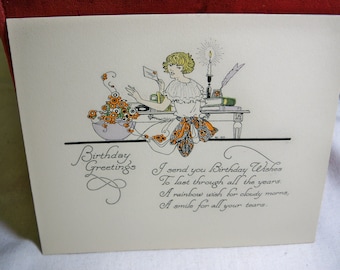 Wonderful unused hand colored 1920’s-30’s Birthday card pretty deco lady in art deco apron ,flowers sits at desk books,candle, artist signed