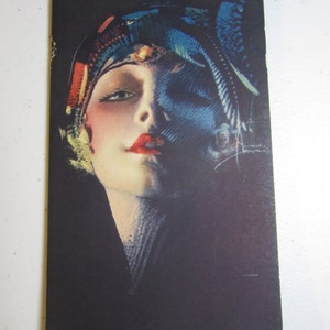 May include: A vintage postcard featuring a woman with a colorful head scarf and a dark background.
