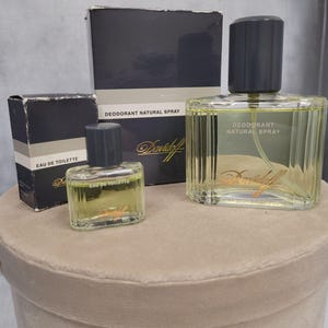 Könnte beinhalten: Eine Sammlung von Davidoff-Düften, darunter eine Flasche Eau de Toilette und eine größere Flasche Deodorant Natural Spray. Die Flaschen sind klar mit einer hellgelben Flüssigkeit und dunkelgrauen Kappen. Die Verpackung ist dunkelblau mit weißem Text.