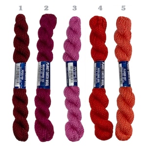 May include: Five skeins of Planet Earth Wool yarn in various shades of red, pink, and orange. The colors include Brick 005, Heartthrob 131, Girlfriend 129, Sizzling 808, and Flambe 007. Each skein is labeled with the brand and color name.