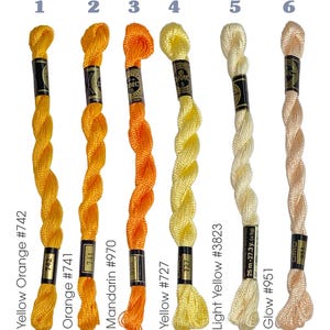 May include: Six spools of DMC embroidery floss in shades of yellow, orange, and light peach. The colors are labeled with their names and numbers: Yellow Orange #742, Orange #741, Mandarin #970, Yellow #727, Light Yellow #3823, and Glow #951.