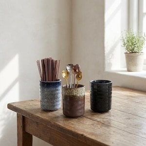 May include: A set of three ceramic nesting bowls in graduating sizes. The bowls feature a speckled, off-white glaze with a slightly textured surface. The largest bowl is approximately 6 inches in diameter.
