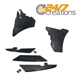 May include: Black textured automotive parts, including several irregularly shaped pieces and smaller components. The parts are arranged against a white background. The logo "24/7 creations" is in the upper right corner.