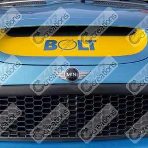 Pode incluir: Close-up da capota azul clara de um carro com uma faixa amarela e a palavra "BOLT" em azul. Um emblema prateado "MINI" está centrado abaixo da entrada de ar, acima de uma grelha preta em favo de mel.