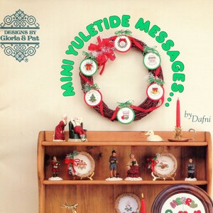Peut inclure: Une collection de modèles de point de croix pour des décorations et des ornements de Noël. Les motifs comprennent une couronne, une chaussette, un arbre et un cœur. Le livre est intitulé "Mini Yuletide Messages" par Dafni. Livre 46, 6,00 €.