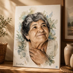 Puede incluir: Un lienzo rectangular con un retrato al estilo acuarela de una persona mayor con cabello gris, vistiendo una prenda blanca. La imagen incluye detalles de hojas verdes y la palabra Grandma escrita en cursiva en la esquina inferior izquierda.