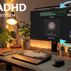 May include: A home office setup with a computer monitor displaying the "FocusBit" application, a keyboard, and a laptop. The text "THE ADHD FOCUS SYSTEM" is visible. The image also includes plants, a desk lamp, and a coffee mug, creating a productive workspace.