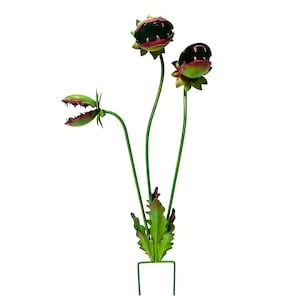May include: A metal garden stake featuring three stylized carnivorous plants. The plants have green stems and leaves, with red and green flower heads that resemble open mouths. The stake has a green, U-shaped base.