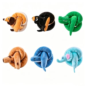 Op de afbeelding: Een verzameling van zes pluche dieren, elk opgerold in een cirkelvorm. De set bevat een beige en witte hond, een zwarte en beige hond, een groene krokodil, een bruine beer, een blauwe haai en een lichtblauwe olifant met roze oren.