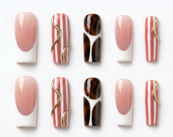 Può includere: Un set di dieci unghie finte con vari design, tra cui la classica manicure francese, strisce verticali rosse e bianche con accenti dorati ondulati e un motivo tartarugato marrone scuro con dettagli bianchi, disposte su due file.