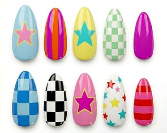 May include: A collection of ten artificial nails in various designs. The nails feature patterns such as stars, stripes, and checkered designs in a variety of colors, including blue, pink, yellow, green, and red. The nails are oval-shaped.