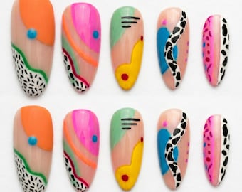 Può includere: Un set di dieci unghie finte a mandorla con vari motivi astratti. I disegni includono blocchi di colore arancione brillante, rosa acceso, verde menta e giallo, stampe animalier in bianco e nero e piccoli accenti a forma di trattini neri.